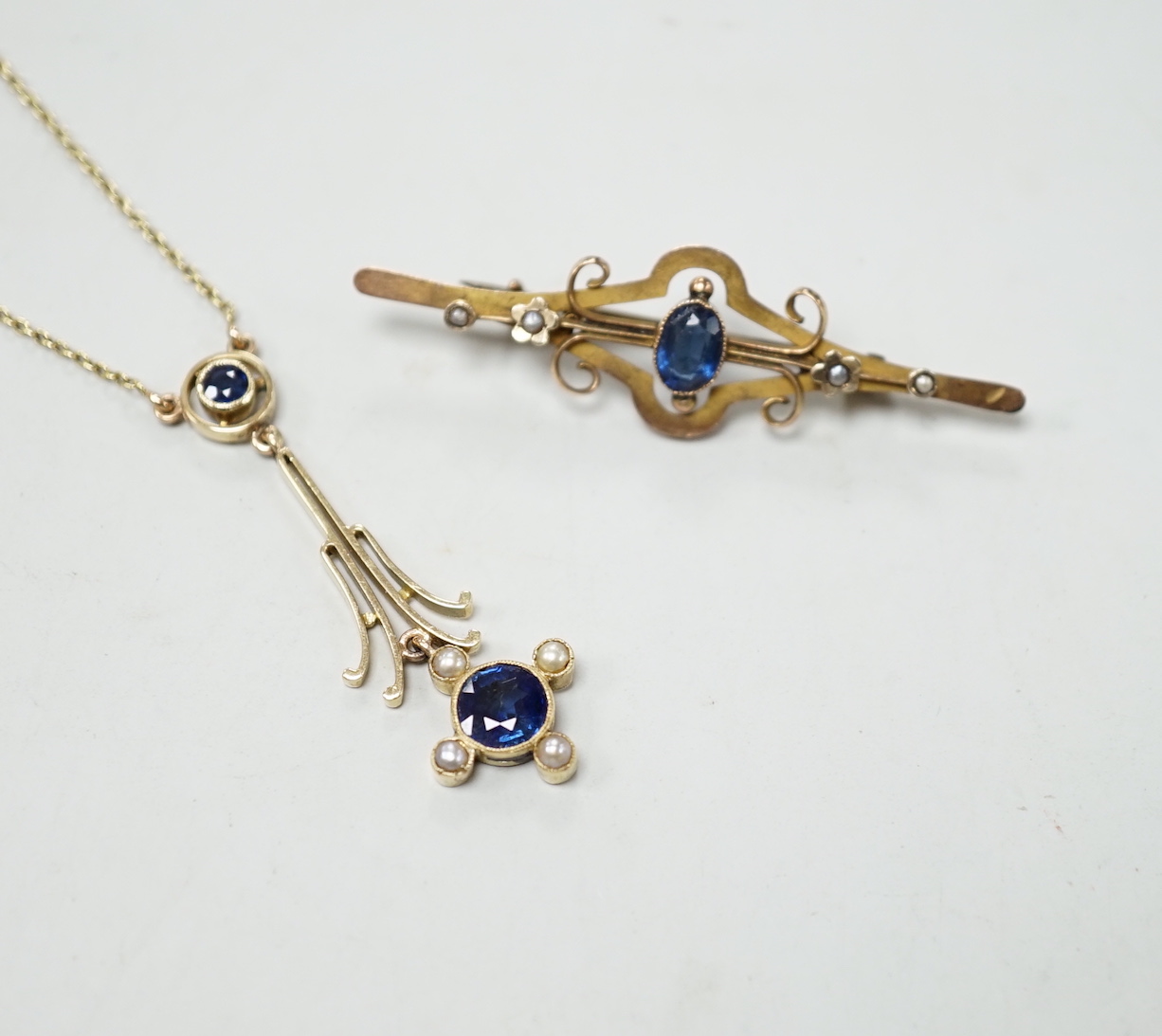An Edwardian 15ct gold, sapphire and seed pearl set drop pendant necklace, overall 52cm, gross weight 4.5 grams and one other yellow metal and gem set bar brooch.